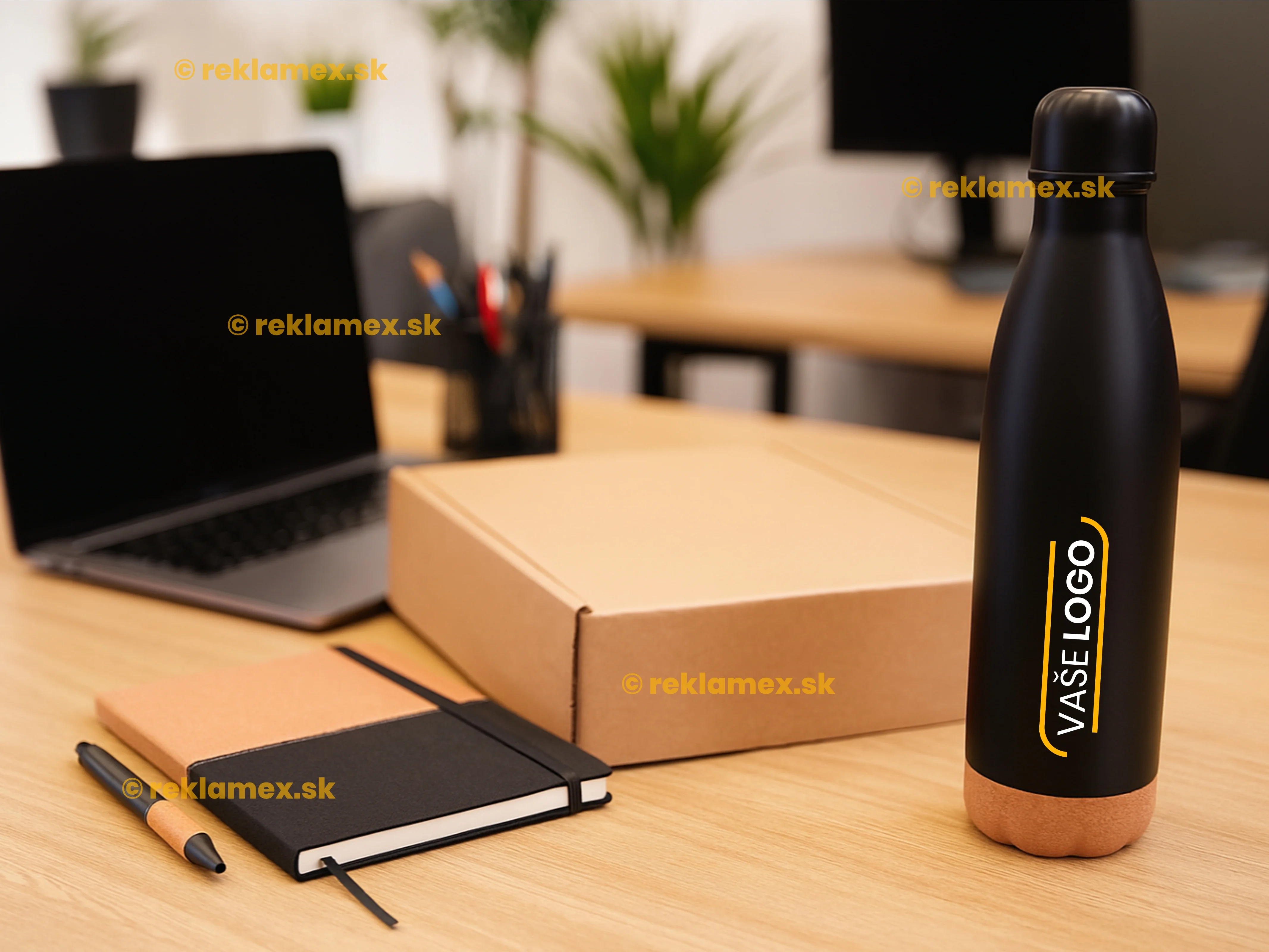 Reálna ukážka firemného darčeka s vlastným logom - kovová čierna fľaša s logom, kovové pera a zápisník položený na stole v kancelárii. 