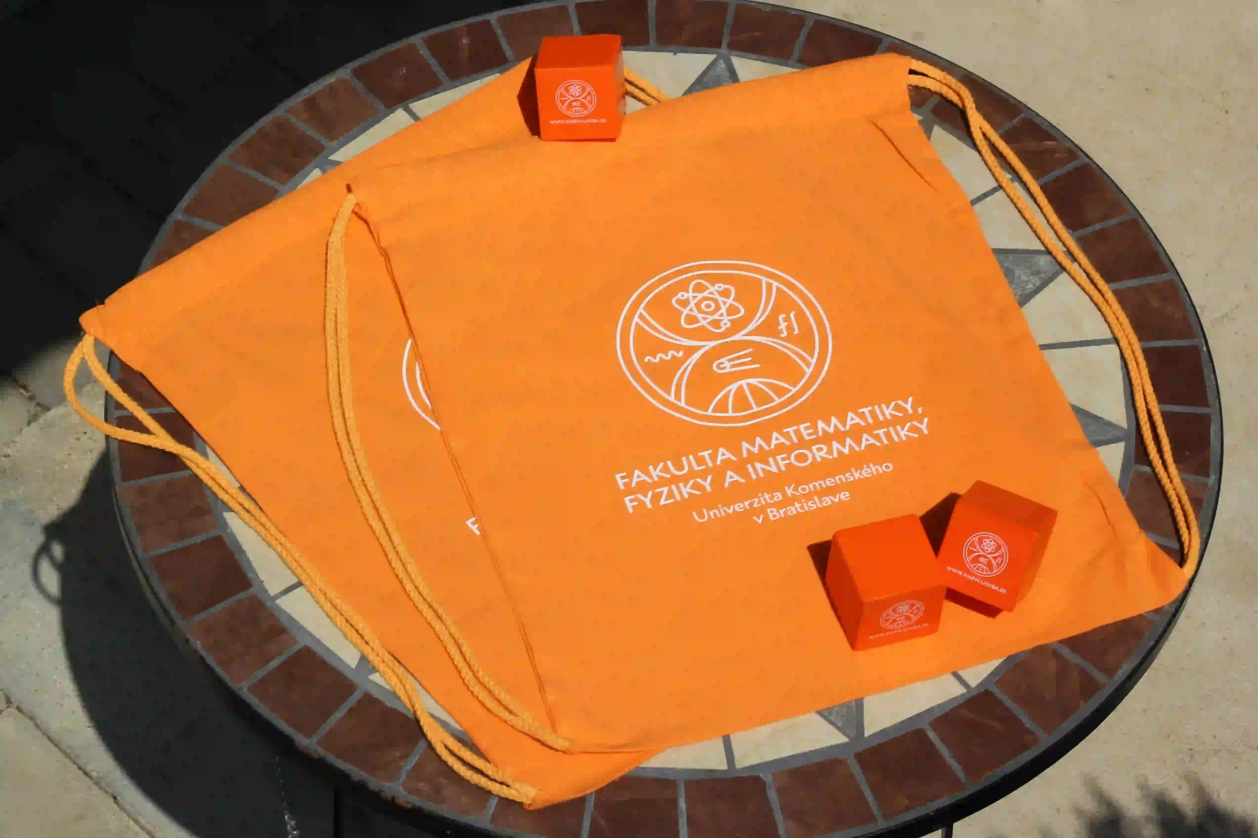 Bavlnené reklamné vaky oranžovej farby s potlačou loga Univerzity.