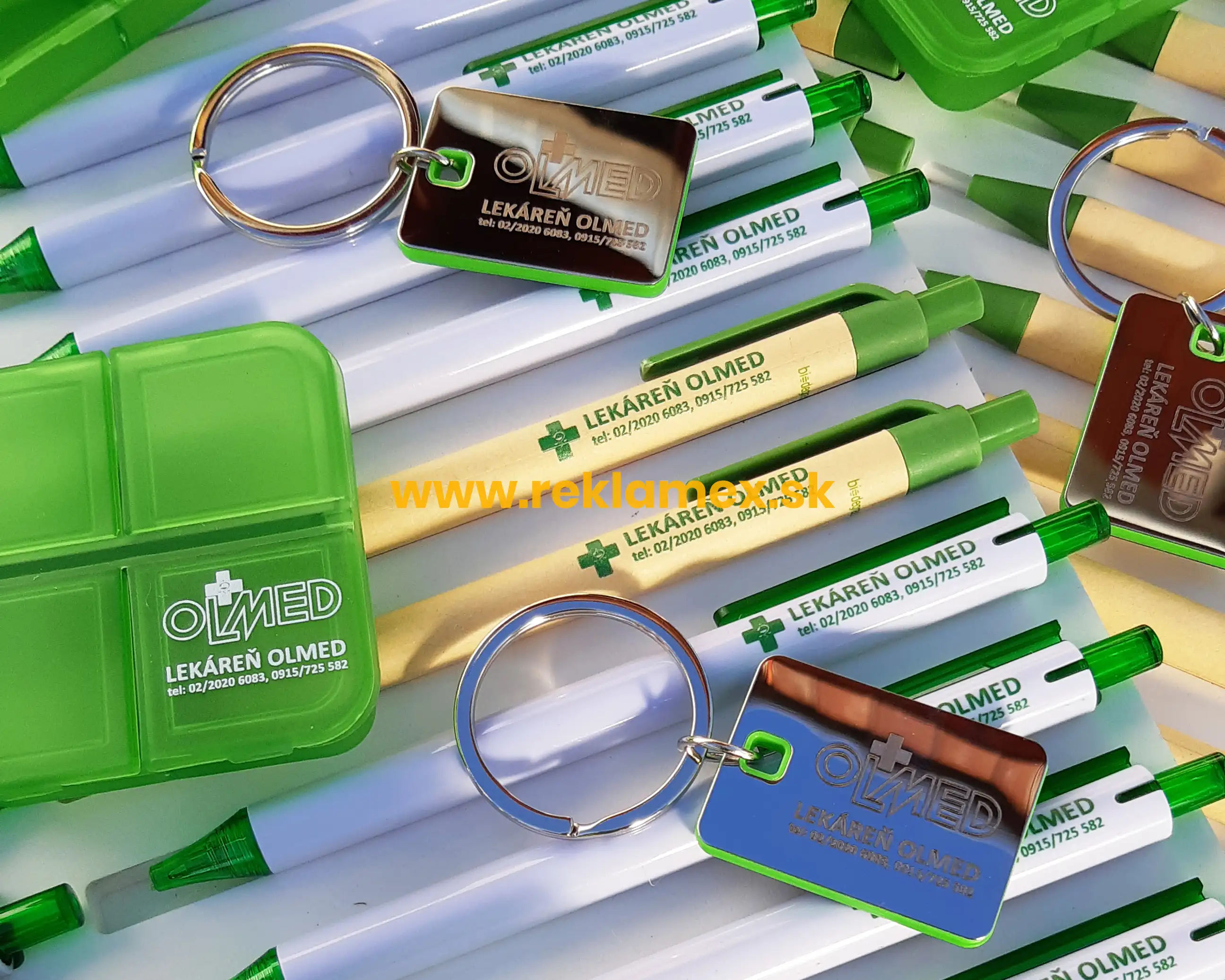 Detailná fotografia zelených reklamných pier a kľúčeniek s potlačou loga pre lekáreň. 